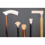λ Five walking canes with ivory handles, including a fist clenching a baton with a silver plated