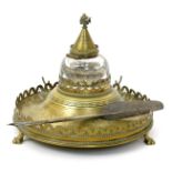 A Hart & Son Aesthetic Movement brass inkwell, the circular tray with pierced crenellated rim,