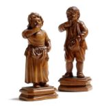 A pair of 19th century continental boxwood models of a boy and a girl, each eating fruit and