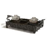 An early Victorian Gothic bronze inkstand, with a pair of associated glass wells flanking a
