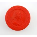 λA 19th century red lacquered snuff box, circular form, the pull-off cover with a raised relief of