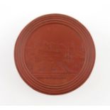 λA 19th century French red Bois Durci snuff box, circular form, the pull-of cover pressed with a