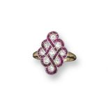 An Edwardian ruby and diamond set lattice form ring, the scrolls of calibre-cut rubies are set