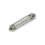 An Art Deco diamond and black onyx bar brooch, set with a line of seven cushion-shaped diamonds