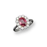 A ruby and diamond cluster ring, the oval-shaped ruby is set with twelve round brilliant-cut