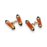 A pair of coral and black onyx cuff links, each cuff link formed with two fluted carved coral