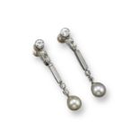 A pair of diamond and natural pearl drop earrings, each pearl suspends from a long