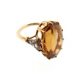 A citrine and diamond ring, the oval-shaped citrine is set within rose-cut diamond shoulders in