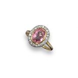 A pink topaz and diamond cluster ring, the oval-shaped pink topaz is set within a surround of