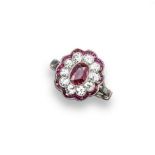 An Edwardian ruby and diamond cluster ring, the oval shaped ruby is millegrain-set within a surround