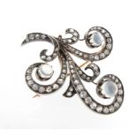 A moonstone and diamond stylised fleur-de-lys brooch, set with three moonstone cabcohons and