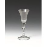 A light baluster glass c.1740, with bell bowl raised on a knopped baluster stem with a long tear