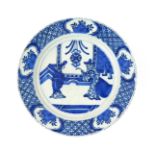 A Delft plate c.1700, painted with a Chinese gentleman and a young maiden in an interior beneath a