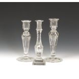 Three glass candlesticks 19th century, two with hollow baluster stems cut with stylized swags