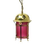 A polished brass hall lantern, the pierced dome with fleur de lys motif, with pink frosted glass