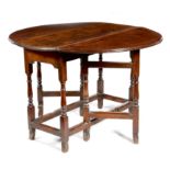 A Queen Anne walnut and oak gateleg table, the oval drop-leaf top on ring turned baluster legs