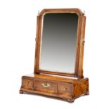 A George II walnut toilet mirror, with a bevelled arched plate within a carved gilt slip and a