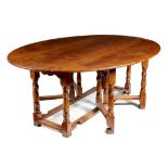 A large 17th century style oak gateleg dining table, the oval drop-leaf top on baluster turned