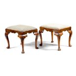 A pair of walnut stools in George II style, each with a drop-in seat, on shell capped cabriole