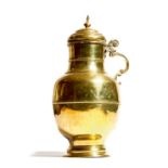 An 18th century Dutch brass milk jug and cover, with a turned finial and a leaf and scroll handle,