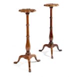 A pair of George I walnut candlestands, each with a quatrelobed top, above a fluted and graduated