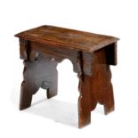 A mid 16th century boarded oak stool, the top with a moulded edge, above a wavy edged frieze and
