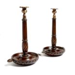 A pair of Victorian mahogany candlesticks, each with a gilt brass leaf cast socket, above a fluted