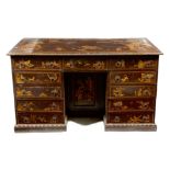 A 19th century brown japanned kneehole desk, the raised chinoiserie decoration painted with gilt