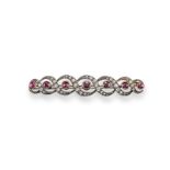 A late 19th century ruby and diamond scroll brooch, set with seven graduated circular-cut rubies