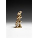 λ A Japanese carved ivory macabre okimono, of a standing skeleton holding a fan, supported by two