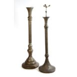 Two Islamic brass floor standing mosque lamps, with pierced decoration, one with script, 19th