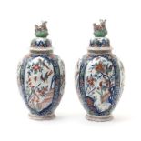 A large pair of Delft vases and covers, probably 18th century, the fluted ovoid forms painted in