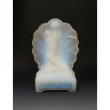 An opalescent glass table lamp, cast in relief with a maiden holding up a globe before a scallop