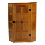 A Robert Mouseman Thompson oak Small Panelled Corner Cupboard, with panelled door, patinated metal