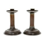 A pair of A.E. Jones Arts and Crafts patinated copper and white metal candlesticks, the stepped