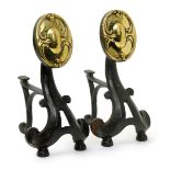 A pair of Art Nouveau polished brass and wrought iron fire dogs, scrolling and pierced tripod base