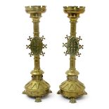 A pair of Gothic Revival brass candlesticks, on three claw feet, the tapering base with sunburst