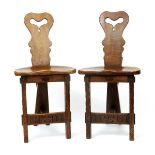 A pair of Arts and Crafts oak hall chairs, possibly American, the back splat carved pierced heart