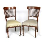 A set of six walnut dining chairs in the manner of E.W. Godwin, slender vertical back splats, on