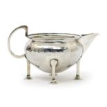 An A.E. Jones silver milk-jug, model no.67, on four square section legs with round pad feet, the