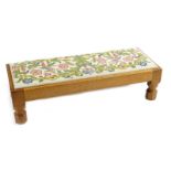 A Robert Mouseman Thompson oak fireside stool with embroidered seat pad, low rectangular section,