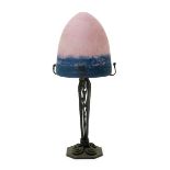 A patinated metal table lamp with glass shade, the glass domed shade graduating from pink to blue