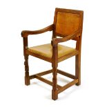 A Robert Mouseman Thompson oak armchair, with carved legs, panel back and tan leather seat, carved