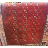 An old Balochi wool work rug, the claret red field interspersed with geometric medallions in