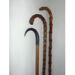 An antique timber walking cane terminating in an applied horn handle, a further bamboo example and a