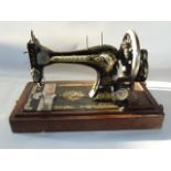 An antique Singer sewing machine raised on a stepped timber base with an associated locking cover