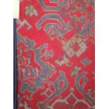 A heavy wool work carpet, the red field interspersed with geometric medallion in shades of blue