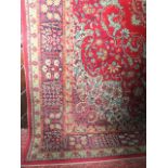 A large wool carpet, the deep red field interspersed with foliate and floral decoration, and set