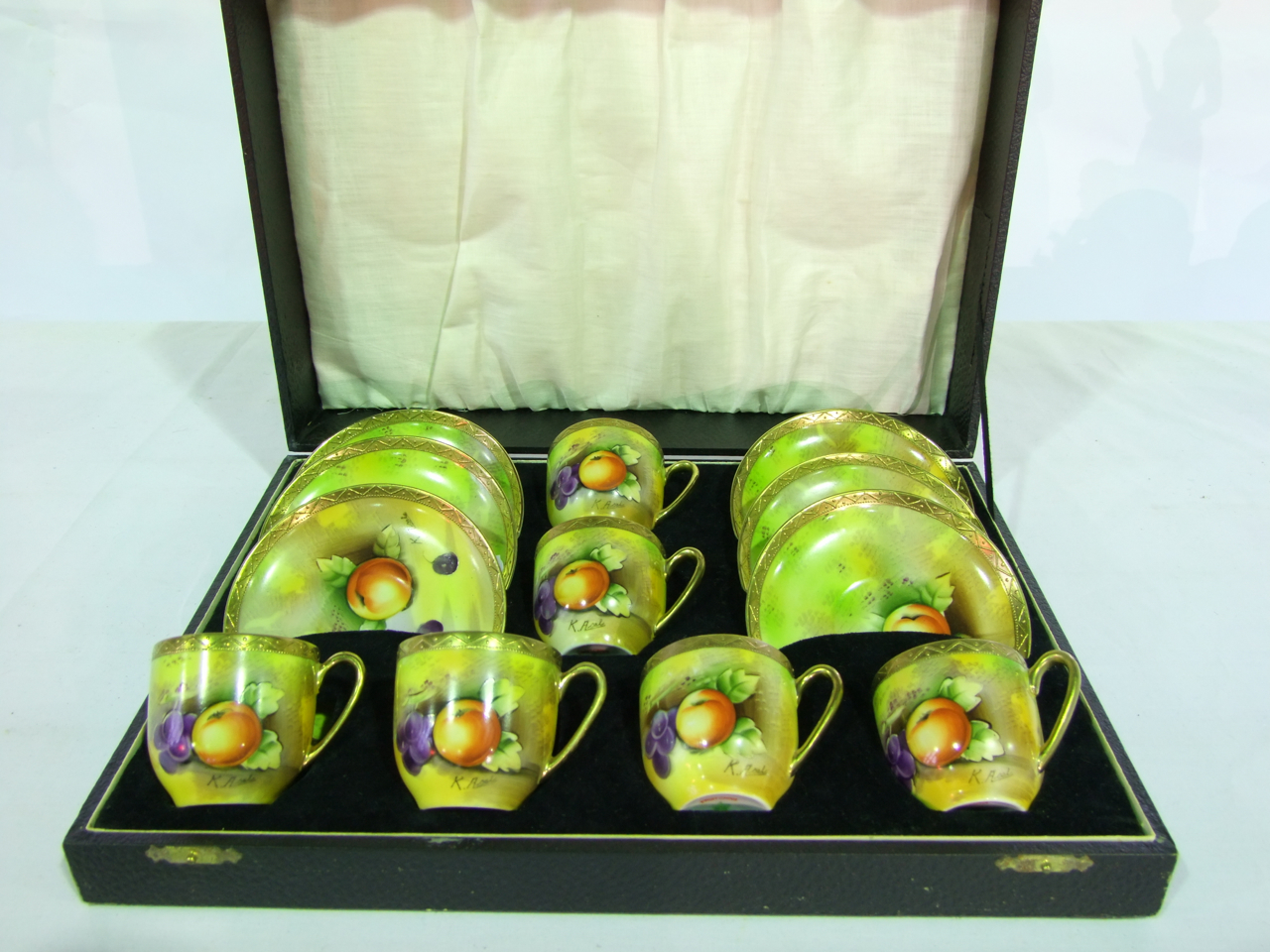 A cased set of six Japanese coffee cups and saucers in the Royal Worcester manner with painted fruit