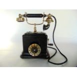 An antique telephone unit with black and metallic house central chromium dial set beneath a cabled